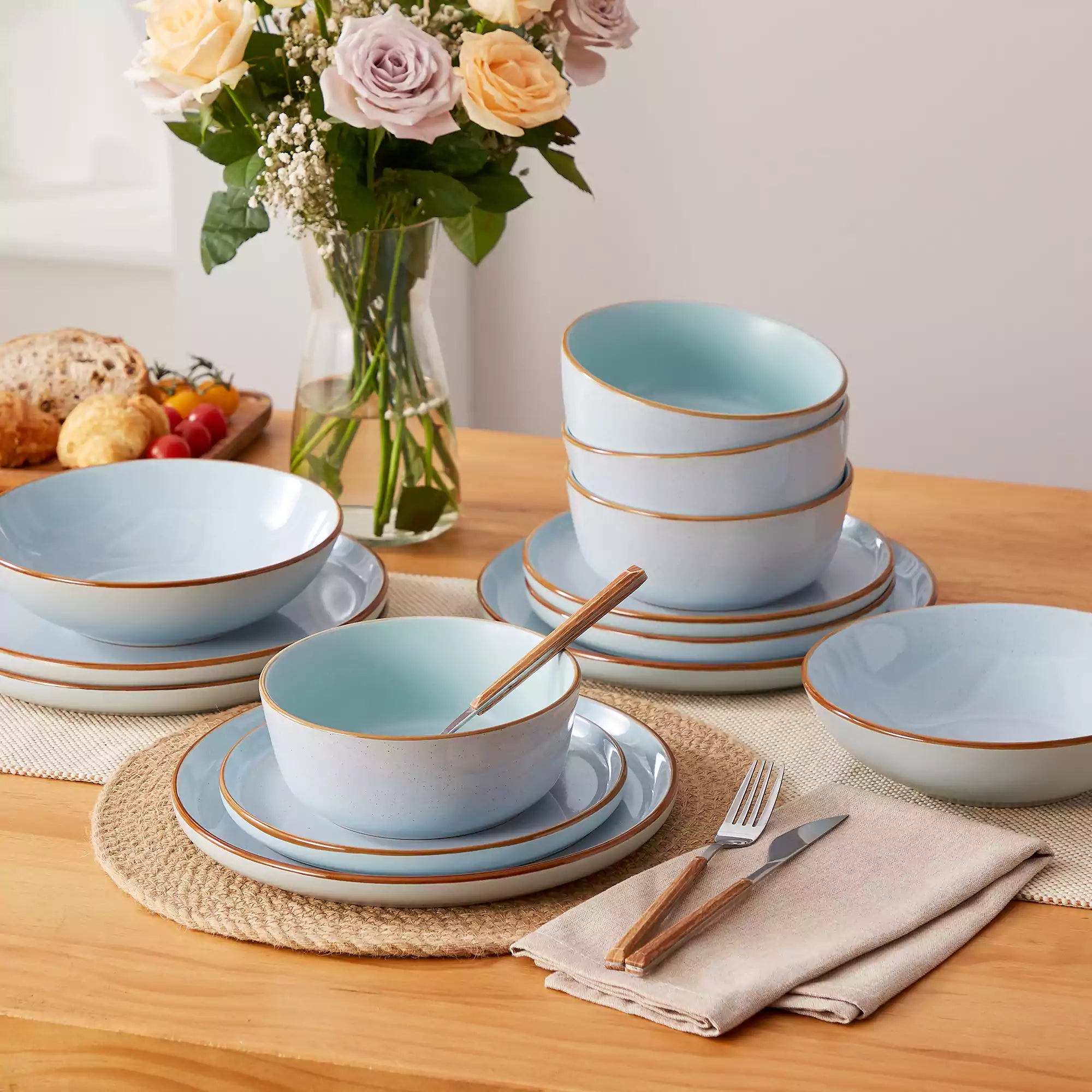 Rustic blue speckled stoneware dinnerware set with lipped-edge plates and bowls arranged on a sunlit modern dining table-vancasso