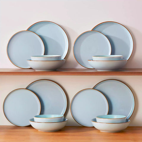 Rustic blue speckled stoneware dinnerware set with lipped-edge plates and bowls arranged on a sunlit modern dining table-vancasso