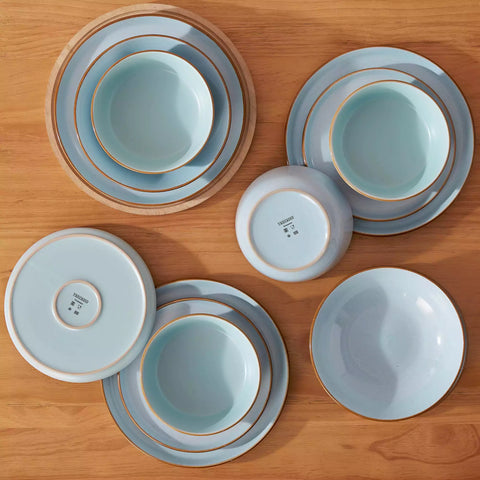 Rustic blue speckled stoneware dinnerware set with lipped-edge plates and bowls arranged on a sunlit modern dining table-vancasso