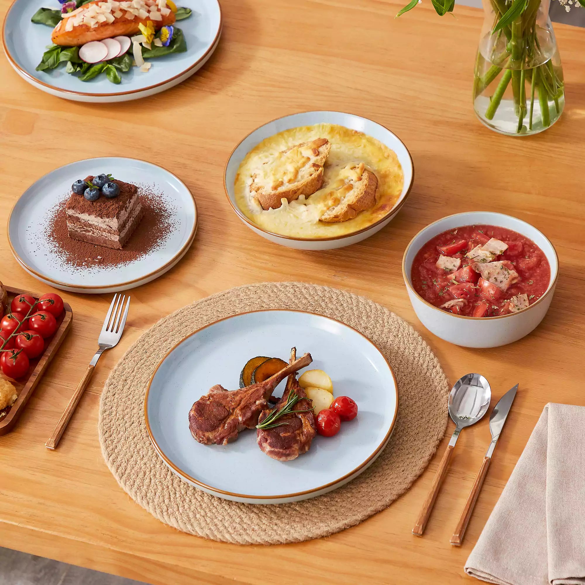 Rustic blue speckled stoneware dinnerware set with lipped-edge plates and bowls arranged on a sunlit modern dining table-vancasso