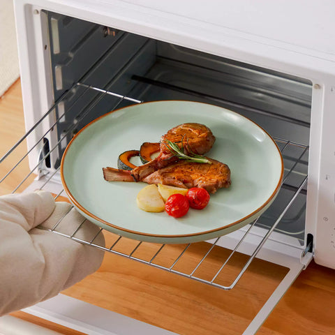 Green rustic stoneware dinnerware set with speckled - lipped-edge plates and bowls on a dining table with flowers and cutlery in a cozy modern kitchen-vancasso