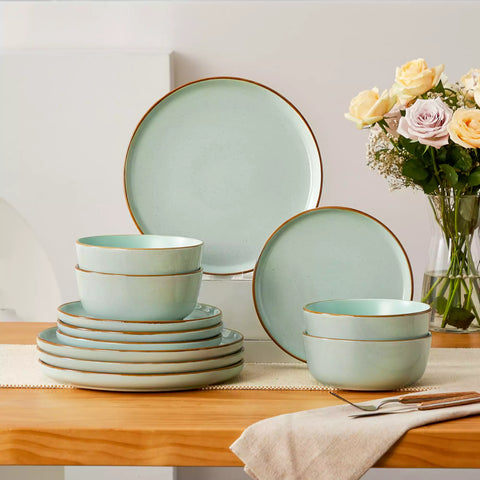 Green rustic stoneware dinnerware set with speckled - lipped-edge plates and bowls on a dining table with flowers and cutlery in a cozy modern kitchen-vancasso