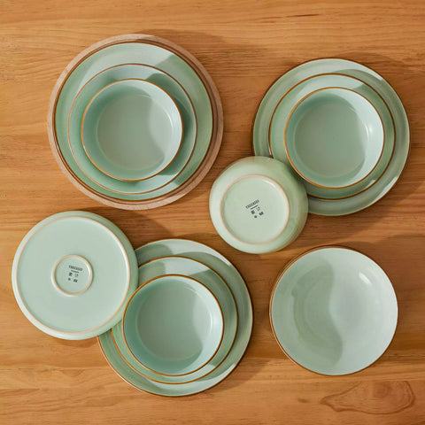 Rustic green speckled stoneware dinnerware set with lipped-edge plates and bowls arranged on a sunlit modern dining table-vancasso