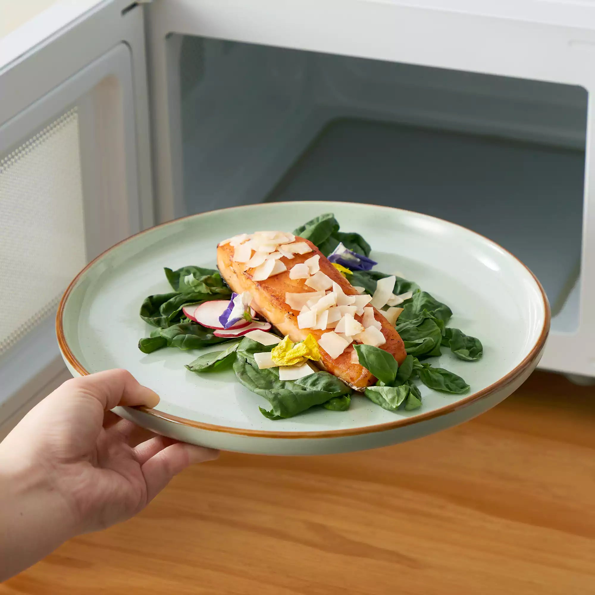 Rustic green speckled stoneware dinnerware set with lipped-edge plates and bowls arranged on a sunlit modern dining table-vancasso