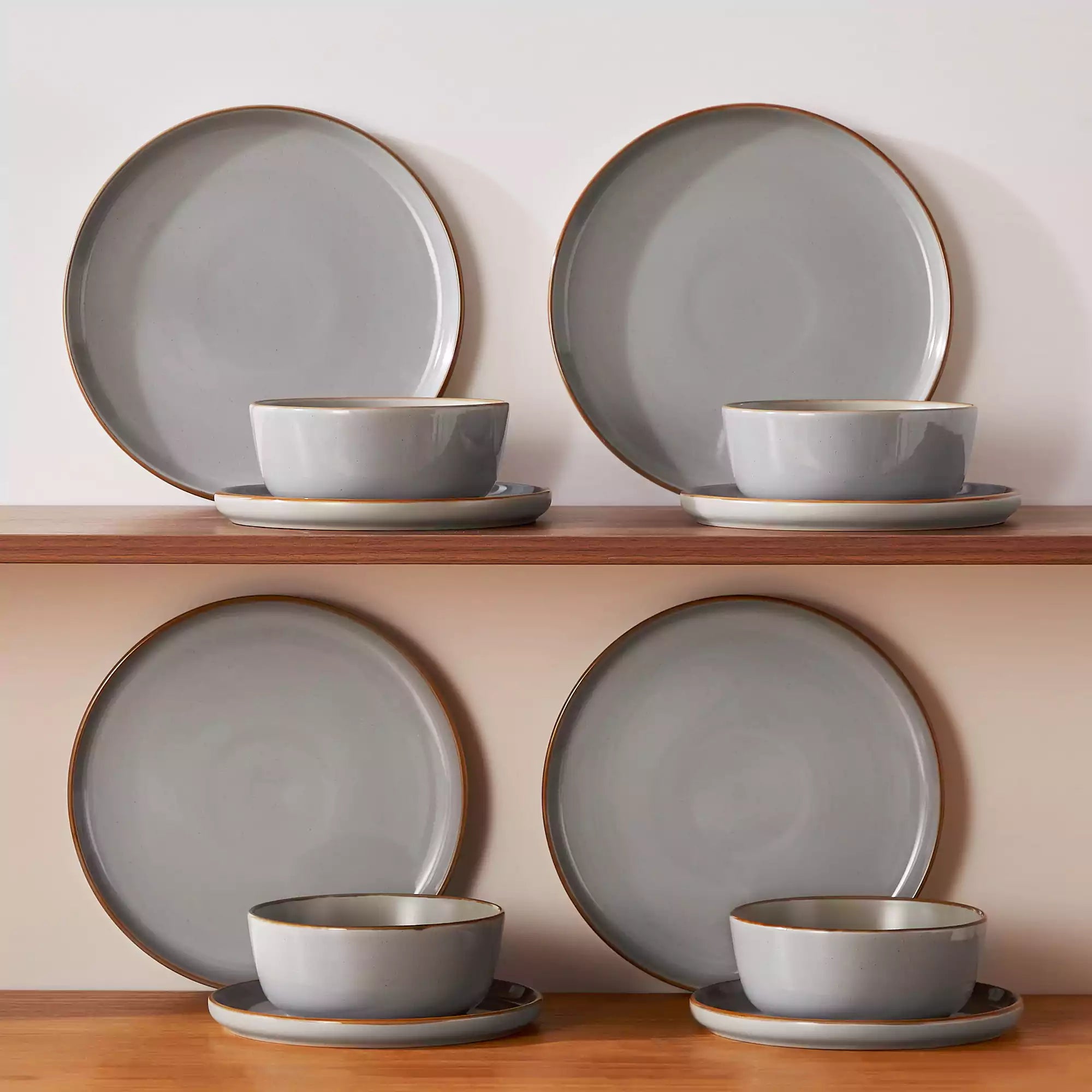 Grey rustic stoneware dinnerware set with speckled - lipped-edge plates and bowls on a dining table with flowers and cutlery in a cozy modern kitchen-vancasso