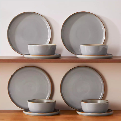 Grey rustic stoneware dinnerware set with speckled - lipped-edge plates and bowls on a dining table with flowers and cutlery in a cozy modern kitchen-vancasso