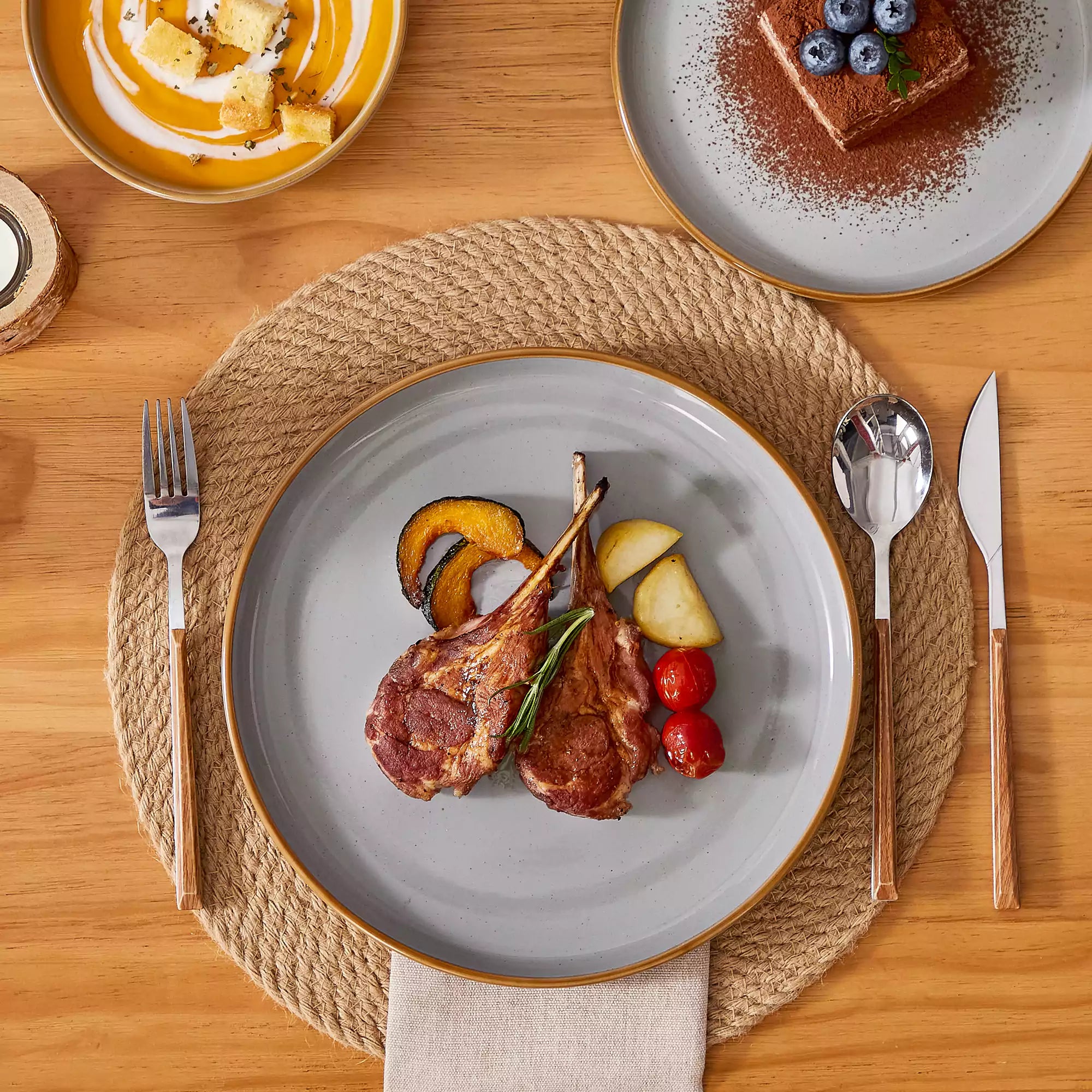 Grey rustic stoneware dinnerware set with speckled - lipped-edge plates and bowls on a dining table with flowers and cutlery in a cozy modern kitchen-vancasso