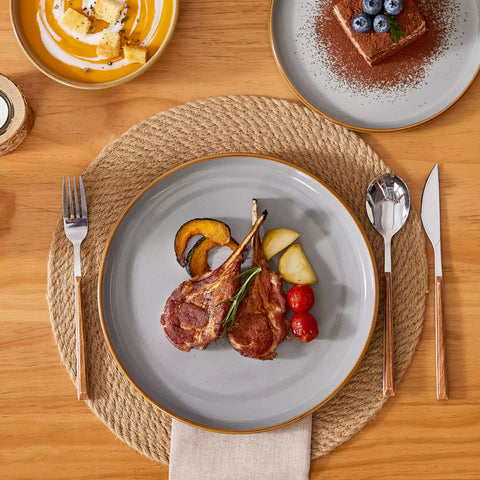 Grey rustic stoneware dinnerware set with speckled - lipped-edge plates and bowls on a dining table with flowers and cutlery in a cozy modern kitchen-vancasso