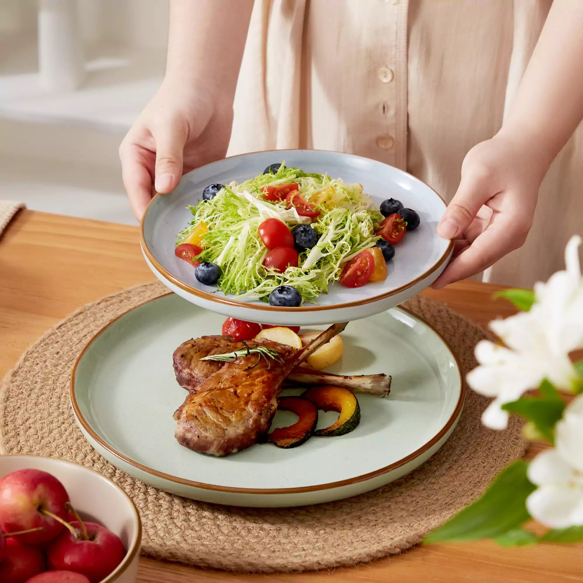 Assorted rustic stoneware dinnerware set with speckled - lipped-edge plates and bowls on a dining table with flowers and cutlery in a cozy modern kitchen-vancasso