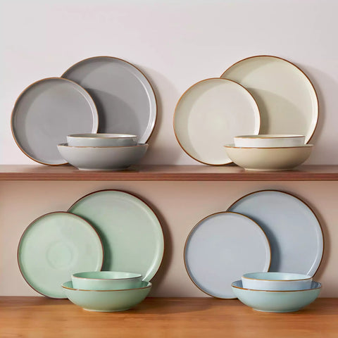 Rustic assorted speckled stoneware dinnerware set with lipped-edge plates and bowls arranged on a sunlit modern dining table-vancasso