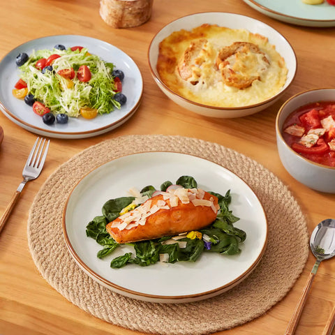 Rustic assorted speckled stoneware dinnerware set with lipped-edge plates and bowls arranged on a sunlit modern dining table-vancasso