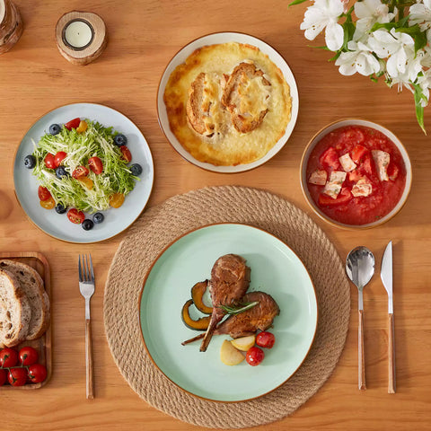 Rustic assorted speckled stoneware dinnerware set with lipped-edge plates and bowls arranged on a sunlit modern dining table-vancasso