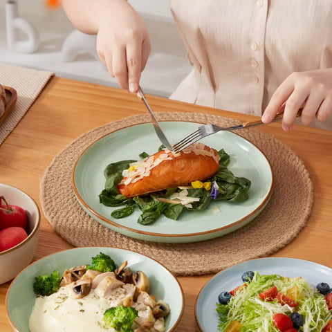 Rustic assorted speckled stoneware dinnerware set with lipped-edge plates and bowls arranged on a sunlit modern dining table-vancasso