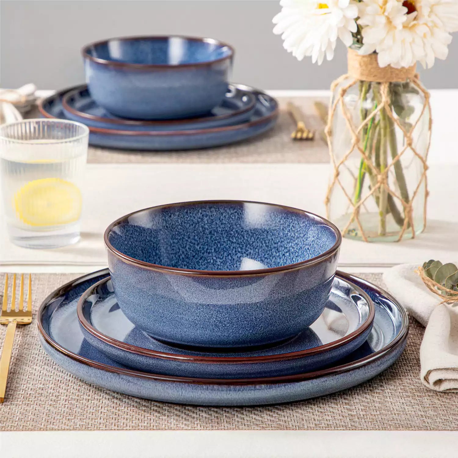 Sata blue stoneware 12 piece dinnerware set with dinner plates salad plates and cereal bowls styled with gold cutlery on textured surface farmhouse reactive glaze lipped edge service for 4