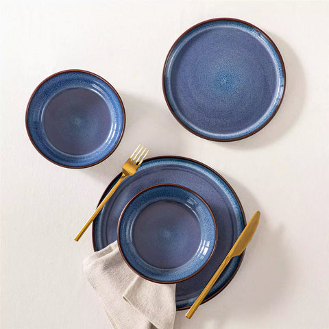 Sata blue stoneware 12 piece dinnerware set with dinner plates salad plates and cereal bowls styled with gold cutlery on textured surface farmhouse reactive glaze lipped edge service for 4