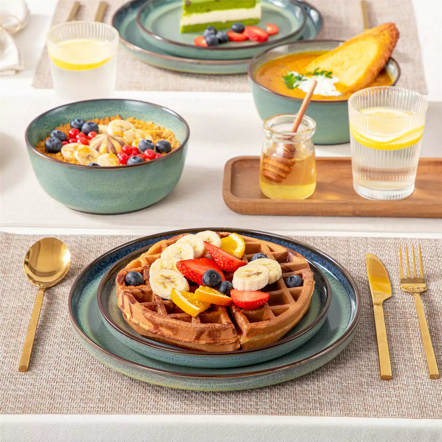 Sata green stoneware 12 piece dinnerware set with dinner plates salad plates and cereal bowls styled with gold cutlery on textured surface farmhouse reactive glaze lipped edge service for 4