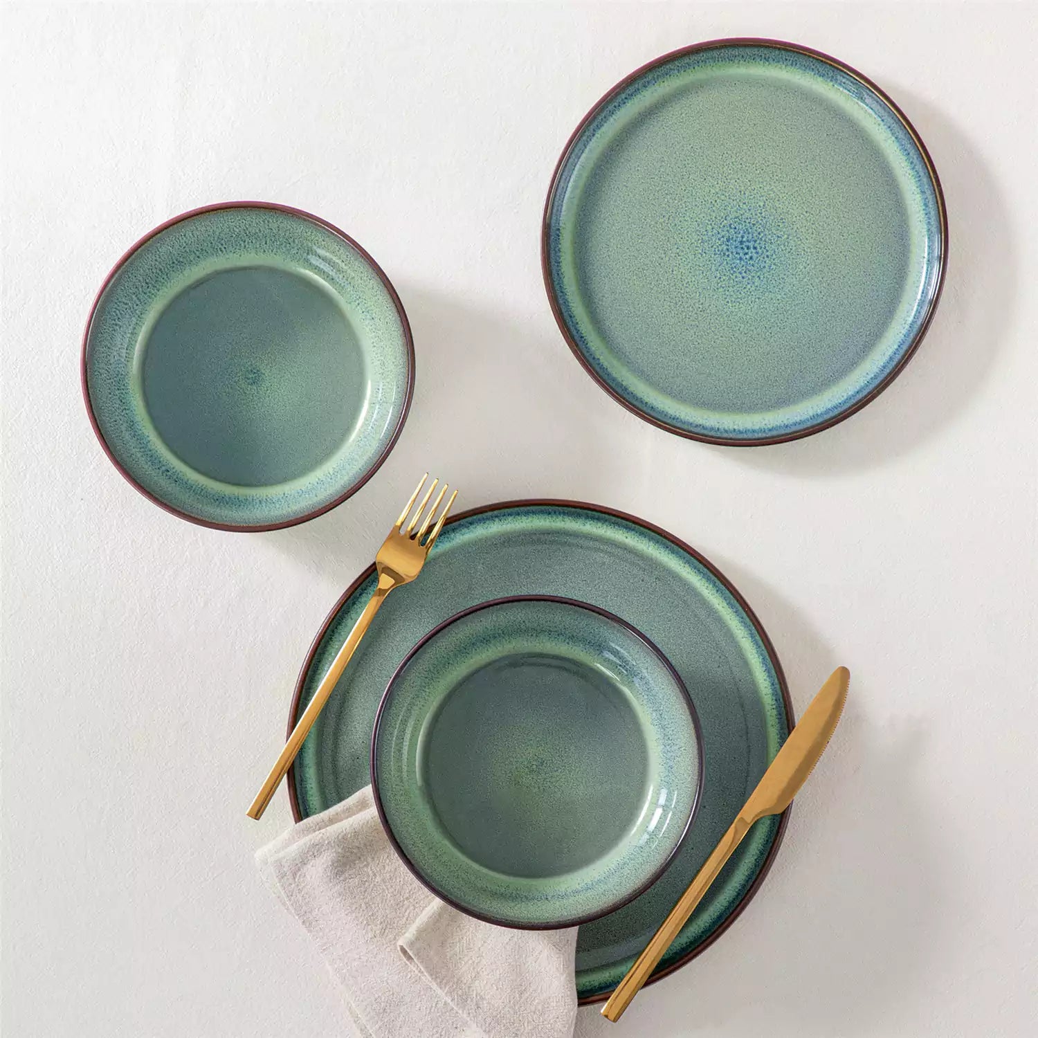 Sata green stoneware 12 piece dinnerware set with dinner plates salad plates and cereal bowls styled with gold cutlery on textured surface farmhouse reactive glaze lipped edge service for 4