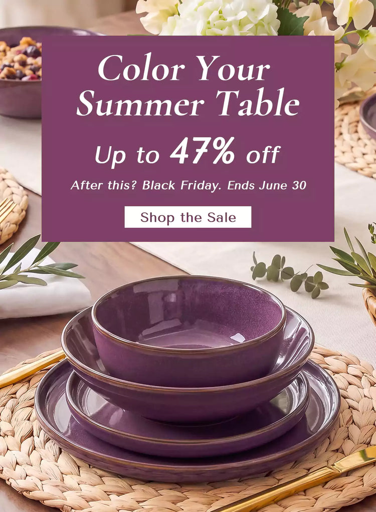 Purple Sata reactive glaze stoneware place setting with layered dinnerware beside white hydrangeas and eucalyptus on a rustic dining table