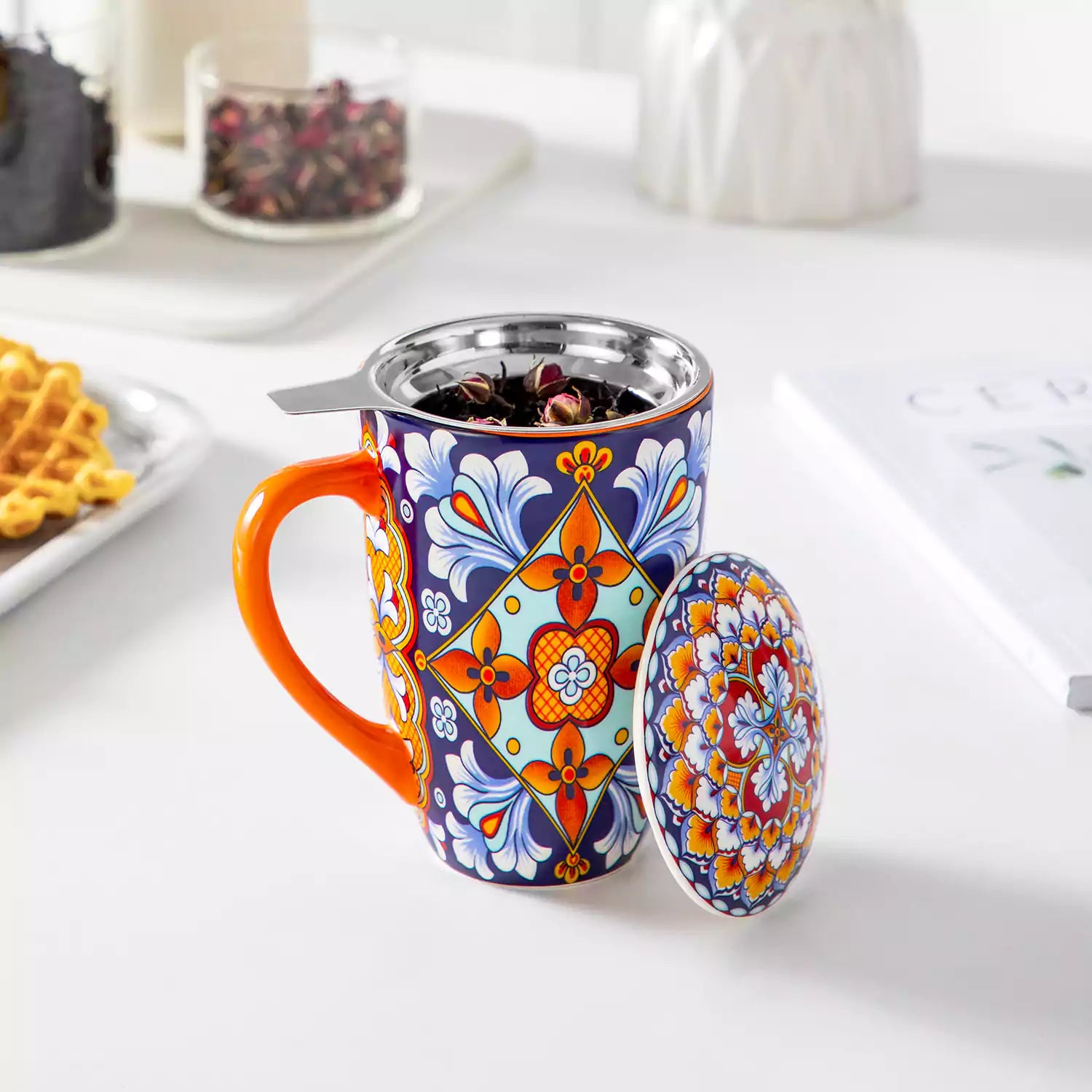 Simi tea mug with infuser and lid colorful bold orange boho chic ceramic coffee cup with spoon and loose tea leaves on white background