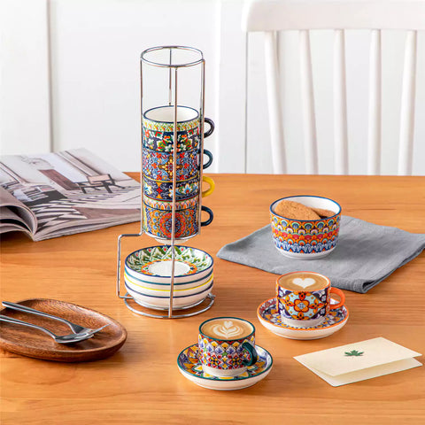 Simi 12 piece porcelain espresso set with 3oz cups and saucers in vibrant boho chic floral patterns on a black metal storage rack with a magazine and napkin on a wooden table