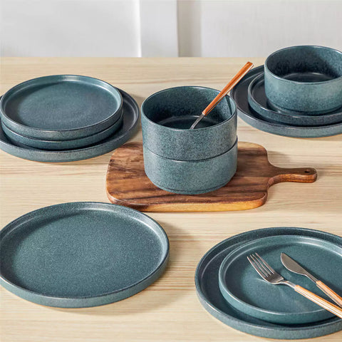 Blue reactive glaze stoneware dinner plates styled with food on rustic wood table with woven placemats modern minimalist tableware set
