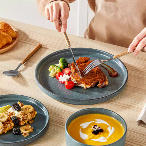Blue reactive glaze stoneware dinner plates styled with food on rustic wood table with woven placemats modern minimalist tableware set