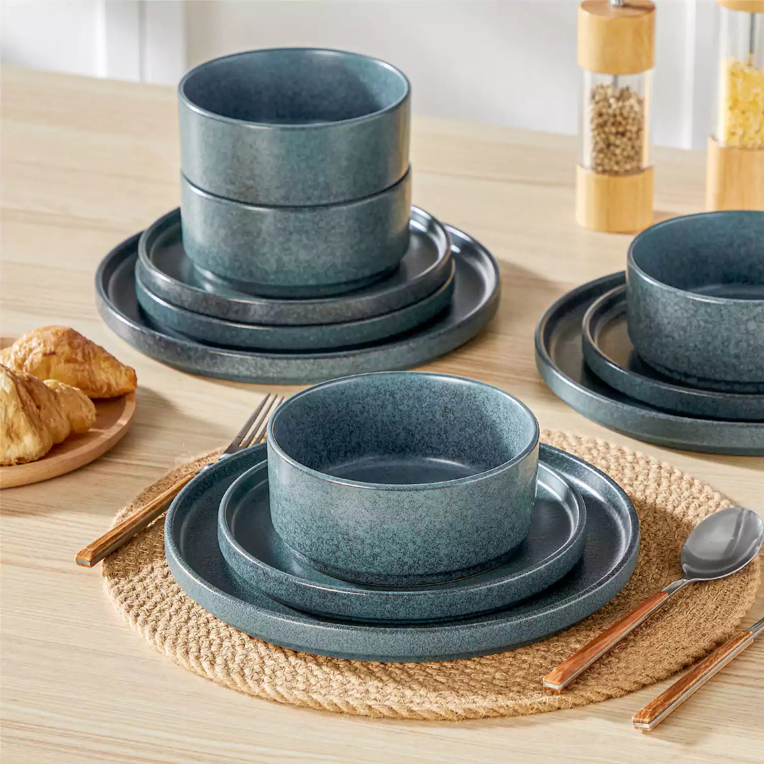 Blue reactive glaze stoneware dinner plates styled with food on rustic wood table with woven placemats modern minimalist tableware set