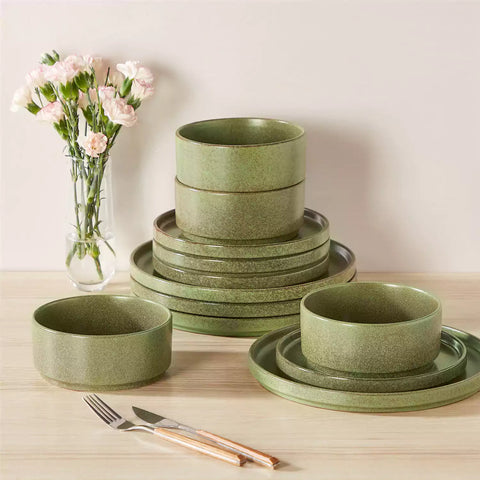 Green reactive glaze stoneware dinner plates styled with food on rustic wood table with woven placemats modern minimalist tableware set