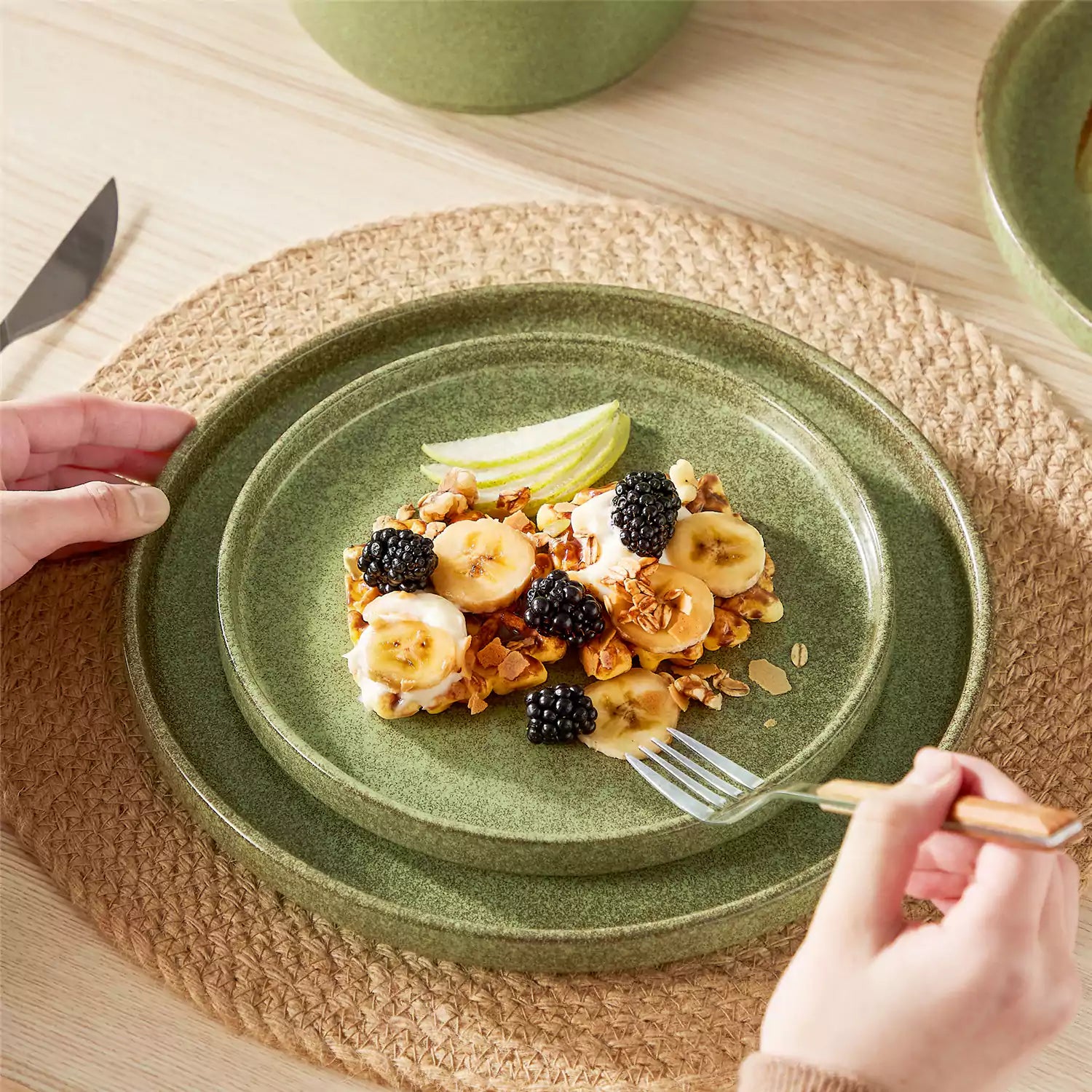 Green reactive glaze stoneware dinner plates styled with food on rustic wood table with woven placemats modern minimalist tableware set