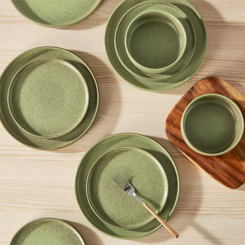 Green reactive glaze stoneware dinner plates styled with food on rustic wood table with woven placemats modern minimalist tableware set
