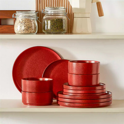 Red reactive glaze stoneware dinner plates styled with food on rustic wood table with woven placemats modern minimalist tableware set