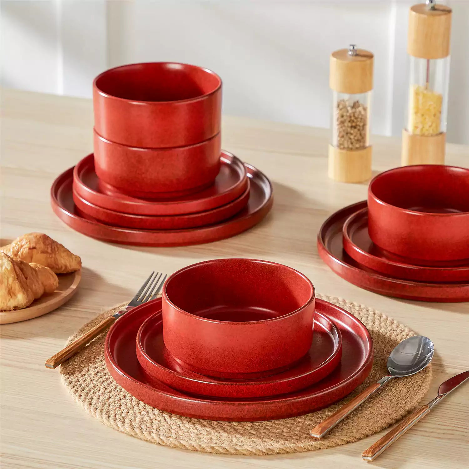 Red reactive glaze stoneware dinner plates styled with food on rustic wood table with woven placemats modern minimalist tableware set
