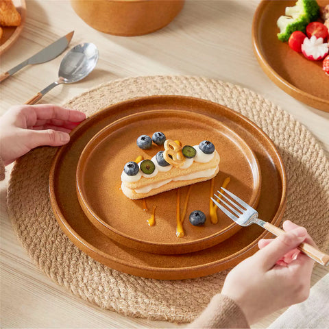 Caramel reactive glaze stoneware dinner plates styled with food on rustic wood table with woven placemats modern minimalist tableware set