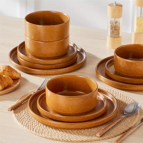 Caramel reactive glaze stoneware dinner plates styled with food on rustic wood table with woven placemats modern minimalist tableware set