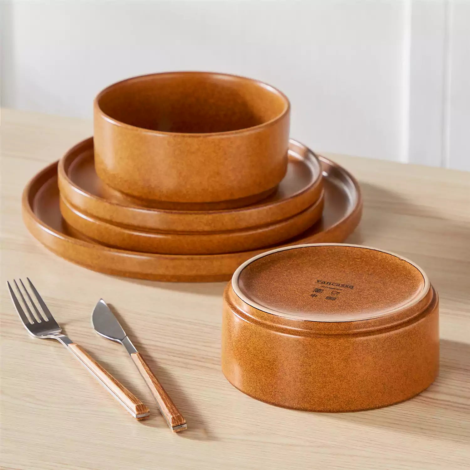 Caramel reactive glaze stoneware dinner plates styled with food on rustic wood table with woven placemats modern minimalist tableware set